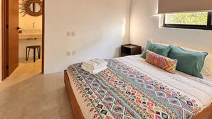 A bedroom with a wooden ceiling, a bed with a colorful quilt, a nightstand, and a window with a view of greenery. - Two bedroom  in Mexico, Tulum (Tulum)