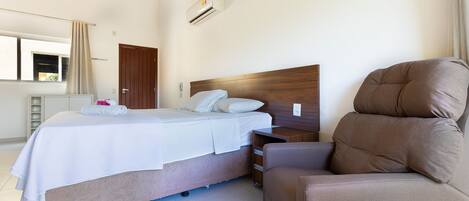 A bedroom with a bed, bedside table, and a brown armchair.