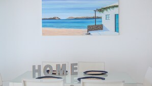 A painting of a beach scene with a house and the word 'HOME' on a table.