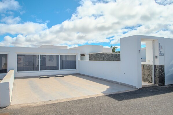 A modern building with a flat roof, large windows, and a stone wall. - Casa El Guanche: Sea Views, Private Pool & Wi-Fi in Playa Blanca (Playa Blanca)