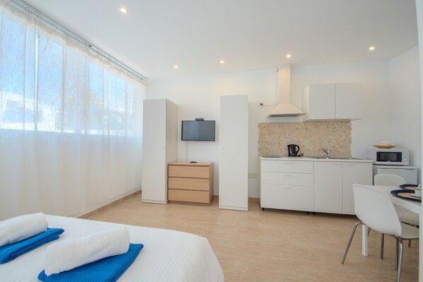 A hotel room with a bed, a desk, a kitchenette, and a TV. - Casa El Guanche: Sea Views, Private Pool & Wi-Fi in Playa Blanca (Playa Blanca)