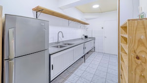 Cocina con refrigerador de acero inoxidable, pileta doble, repisa de madera y salpicadero de azulejos blancos.