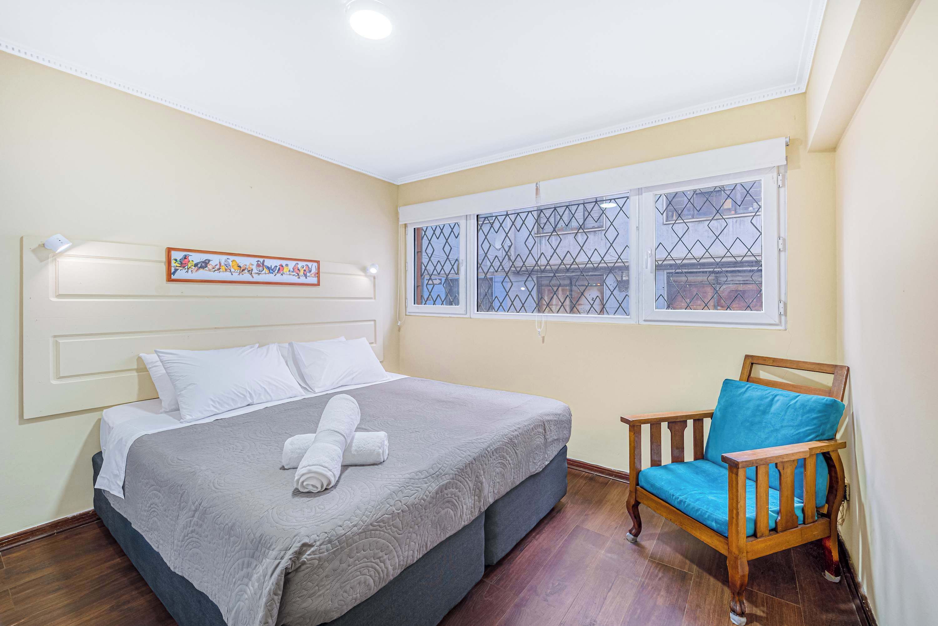 Un dormitorio con una cama, una silla, un ventanal y un adorno en la pared.
