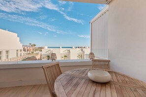 A balcony with a wooden table and chairs, a view of the sea, and a cityscape in the background. - Playa Paraiso Beachfront Apartment (La Vila Joiosa)