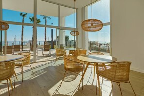 A spacious balcony with wicker furniture, large windows, and a view of palm trees and the sea. - Playa Paraiso Beachfront Apartment (La Vila Joiosa)