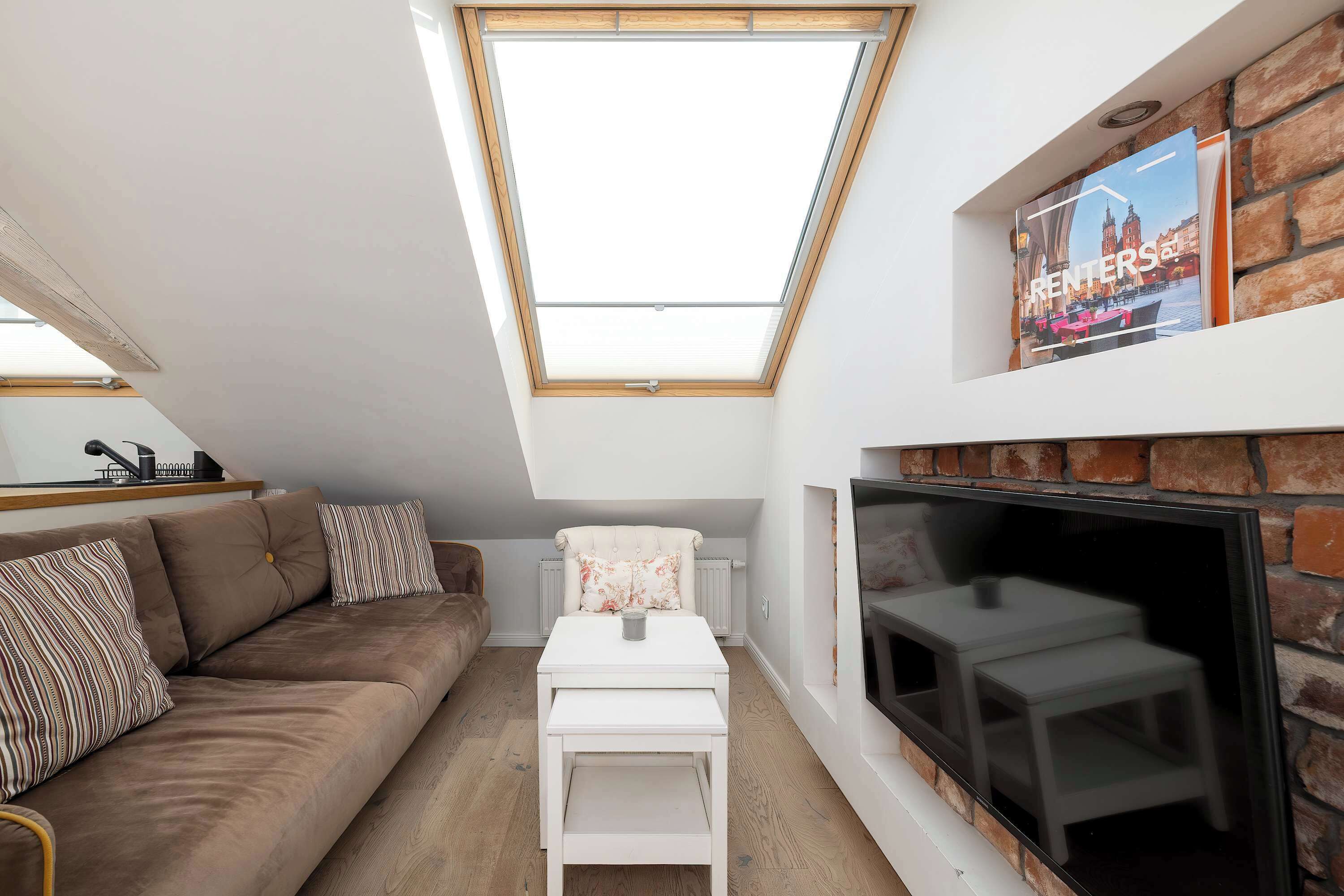 Een moderne loft slaapkamer met dakraam, open haard, bank en televisie.