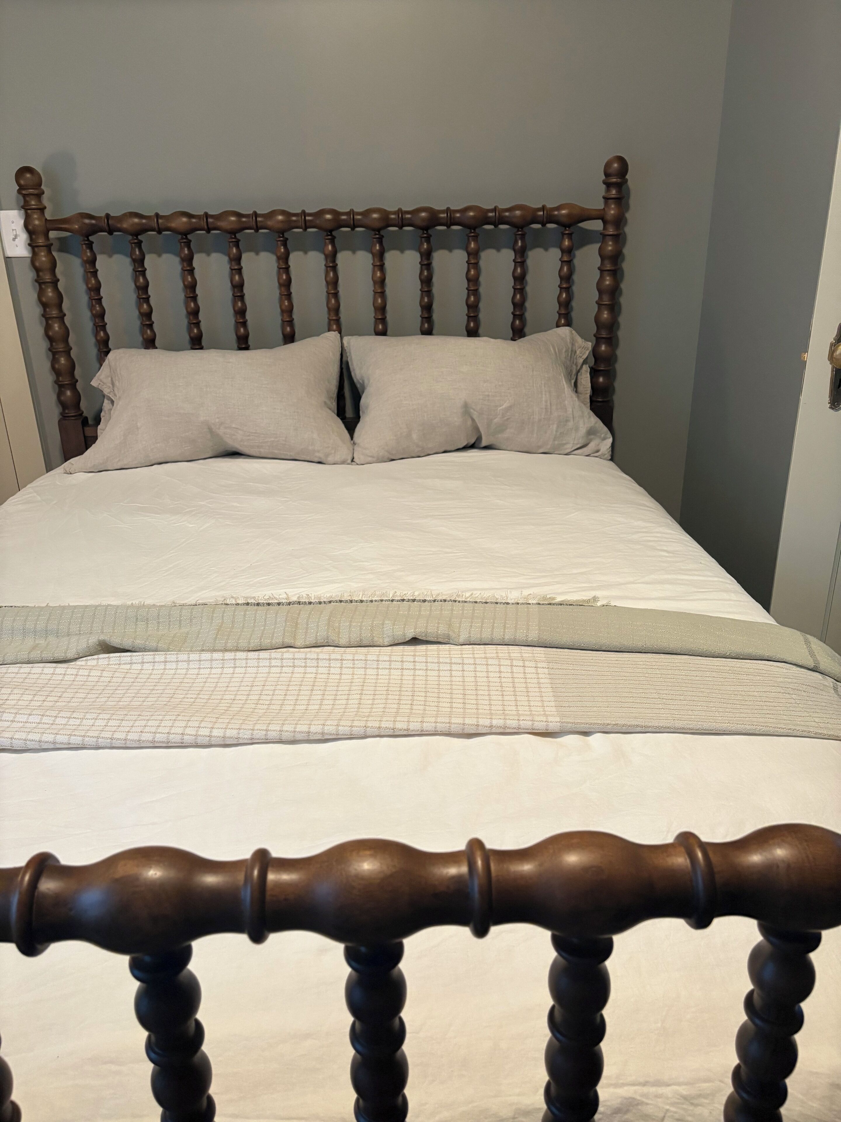 Een bed met een houten hoofdbord en twee kussens.