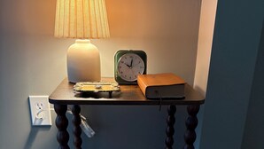 Et sofabord i træ med en lampe, et ur og et par bøger.