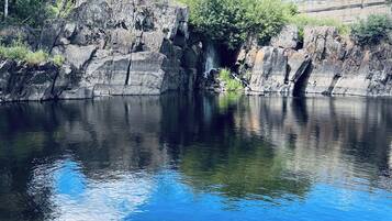 Un riu tranquil amb vores rocoses i un pont al fons.