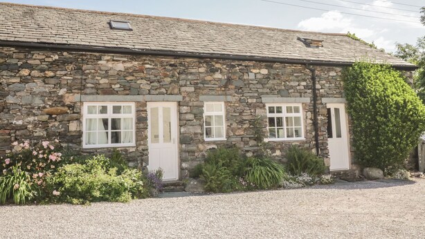 A stone building with three windows and a gravel driveway. - Cottage 1 (Keswick)