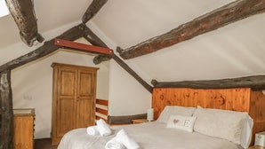 A bedroom with a large bed, wooden headboard, and a wardrobe. - Cottage 1 (Keswick)