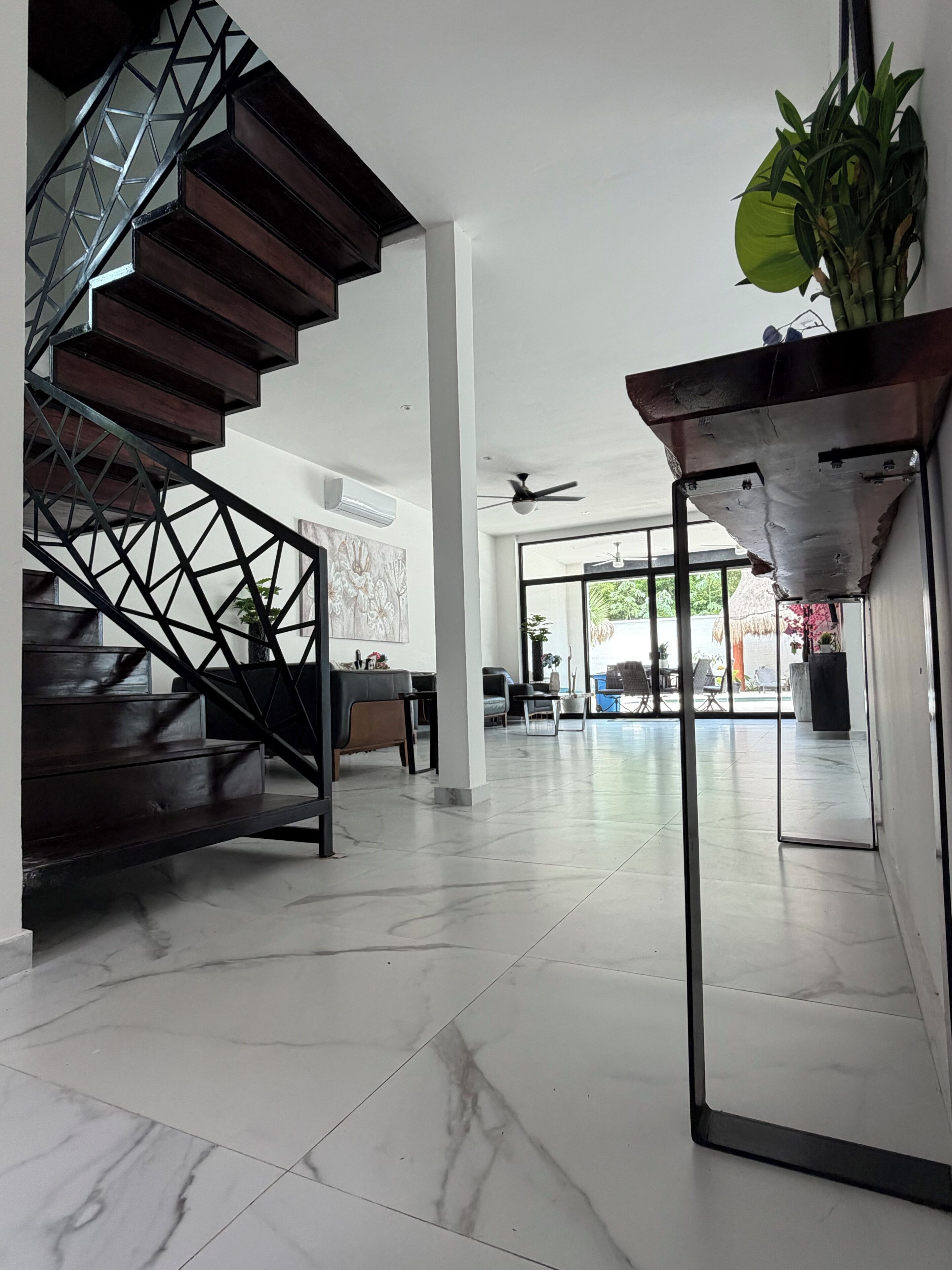 A modern interior with a spiral staircase, a seating area, and a view through large glass doors.
