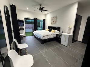 A bedroom with a bed, a desk, a chair, a ceiling fan, and a sliding glass door to a balcony. - Villa CasaYoung "Perfect Family Vacations" Cenotes and Fun Just Minutes Away! (Puerto Morelos)