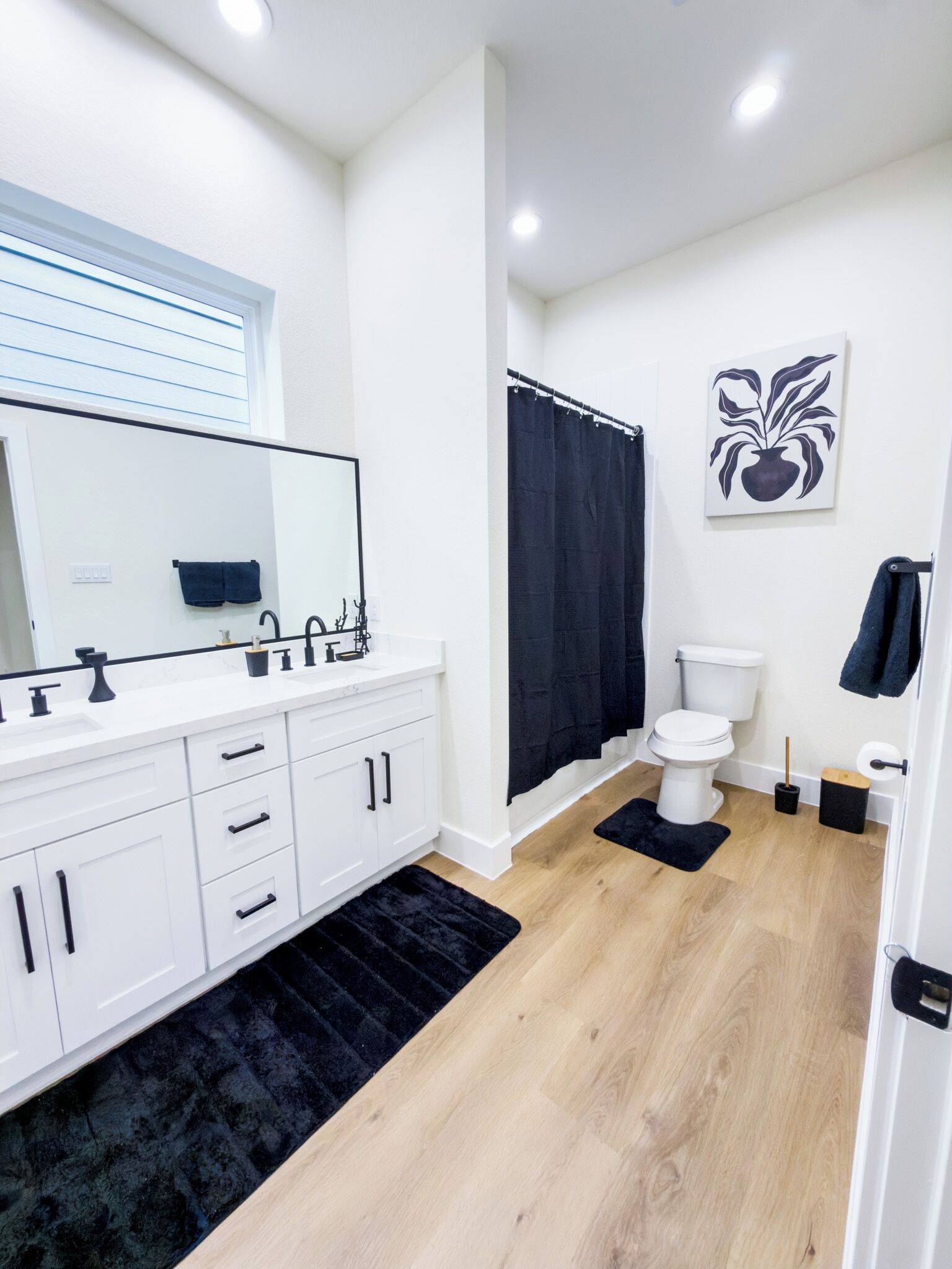 A modern bathroom with a white vanity, black bathtub, and a toilet.