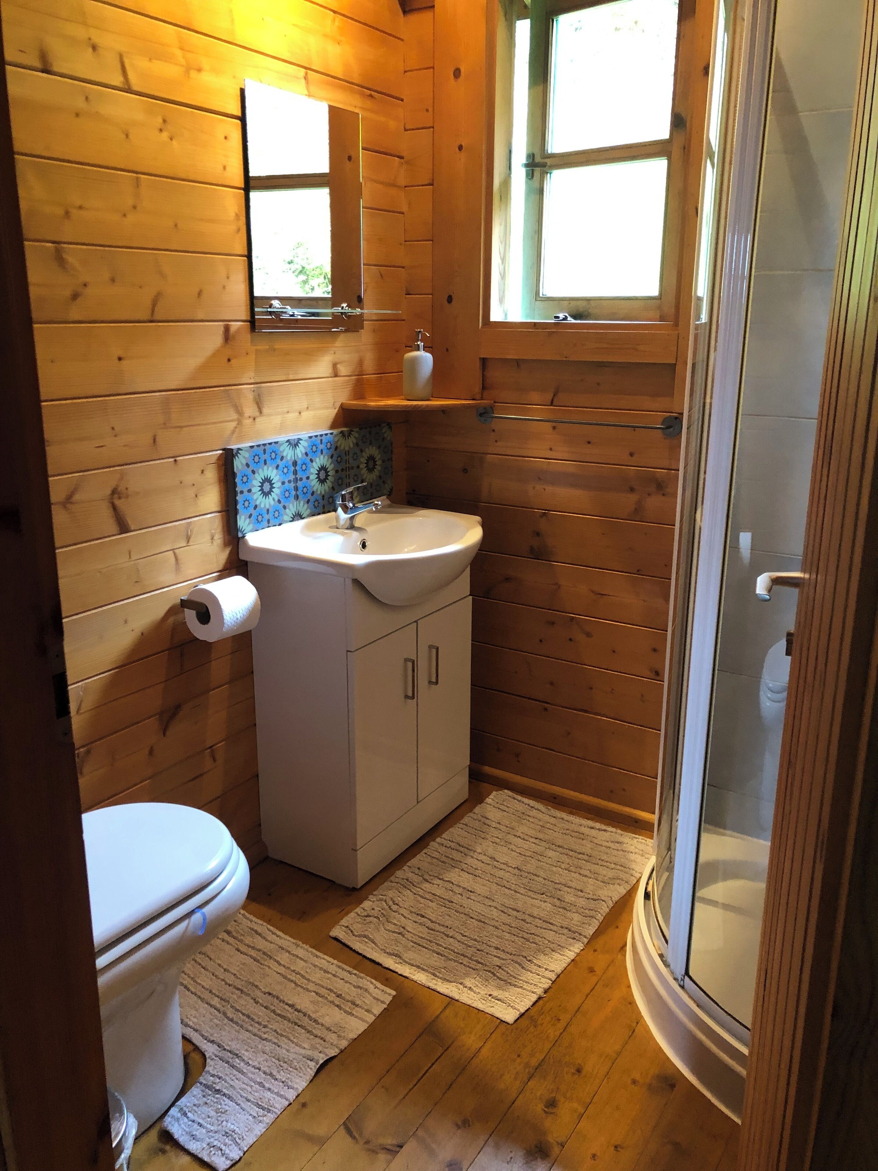 Een betegelde badkamer met toilet, wastafel en douche.