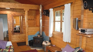 A cozy cabin interior with a wooden interior, a fireplace, a sofa, and a television.