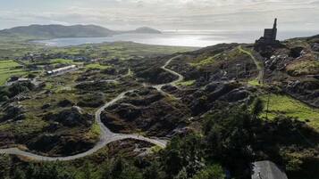 Paisatge costaner amb carretera sinuosa, un edifici petit i vista panoràmica del mar a la distància.