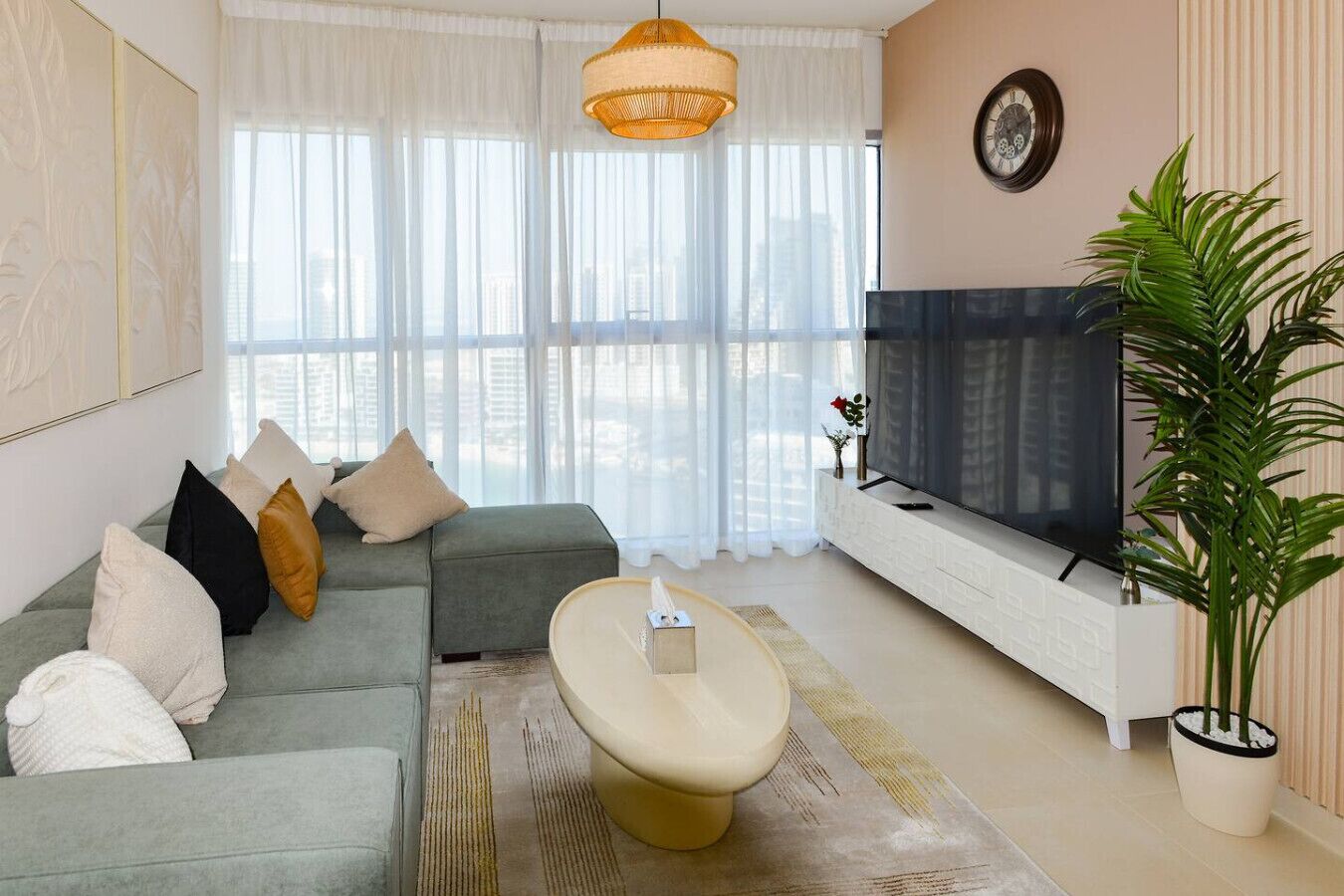 Ein modernes Wohnzimmer mit einem grauen Sofa, einem Flachbildfernseher und einer großen Topfpflanze.