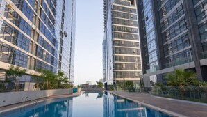 Un moderno edificio residencial con una piscina central rodeada de apartamentos de gran altura.