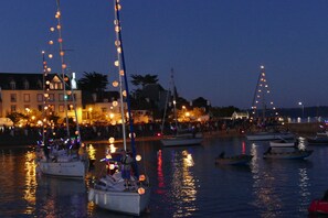 A harbor at dusk with boats docked and illuminated by string lights.