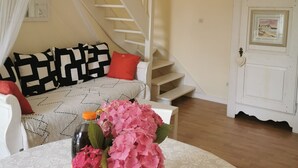 A living room with a staircase, a sofa with patterned cushions, a table with a bottle and flowers, and a door with framed pictures. - 50m beach balcony facing the sea 2P duplex 31 m2 for 2 adults + 2 children, (LOCQUIREC)
