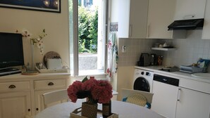 A dining area with a round table, chairs, a television, and a vase of flowers. - 50m beach balcony facing the sea 2P duplex 31 m2 for 2 adults + 2 children, (LOCQUIREC)
