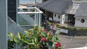 A coastal building with a balcony overlooking the sea, a sign indicating a summer exhibition, and a view of the beach and hills in the distance. - 50m beach balcony facing the sea 2P duplex 31 m2 for 2 adults + 2 children, (LOCQUIREC)