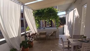 Ein möblierter Außenbereich mit Terrasse, Topfpflanzen und Blick auf die umliegenden Gebäude.