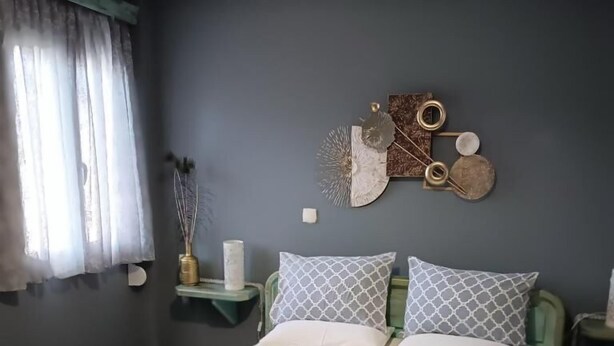 Ein ordentlich bezogenes Bett mit Kissen und Handtüchern, ein Nachttisch mit einer Vase und eine Wanddekoration.