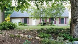 A residential property with a well-maintained garden, a garage, and a house with a pitched roof.