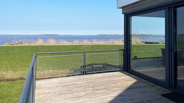 A modern building with a glass balcony overlooking a body of water. - Modern, spacious vacation apartment with a picturesque view of Lake Tjeukesee (Oosterzee)
