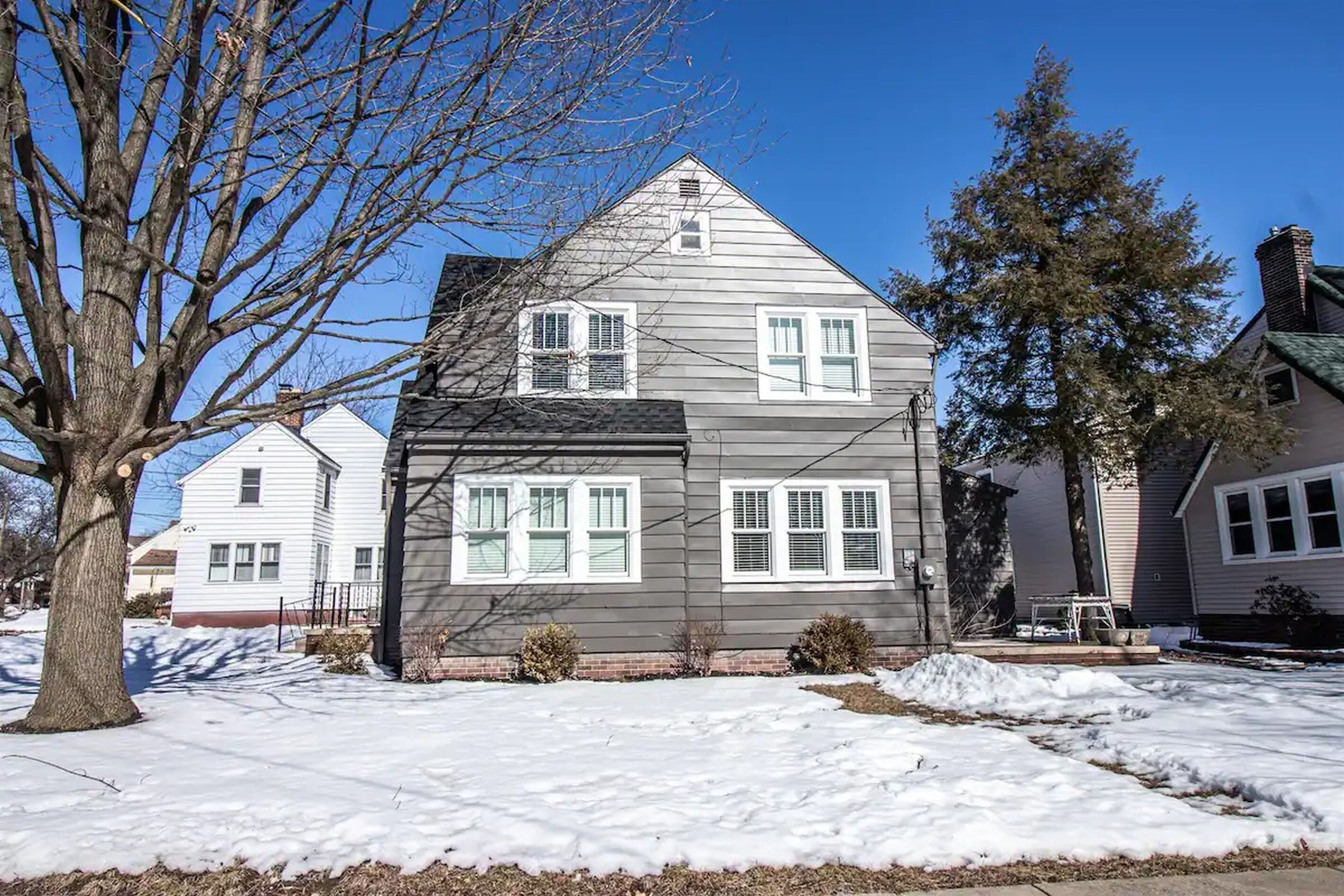 A two-story house with a gabled roof, white siding, and multiple windows.