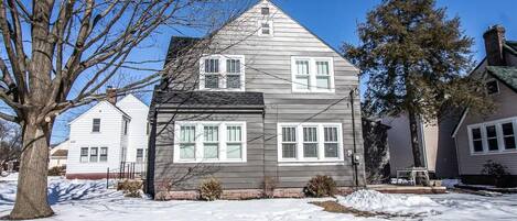 A two-story house with a gabled roof, white siding, and multiple windows.