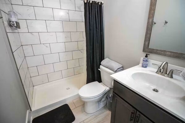 A bathroom with a white toilet, a bathtub, a sink, and a mirror.