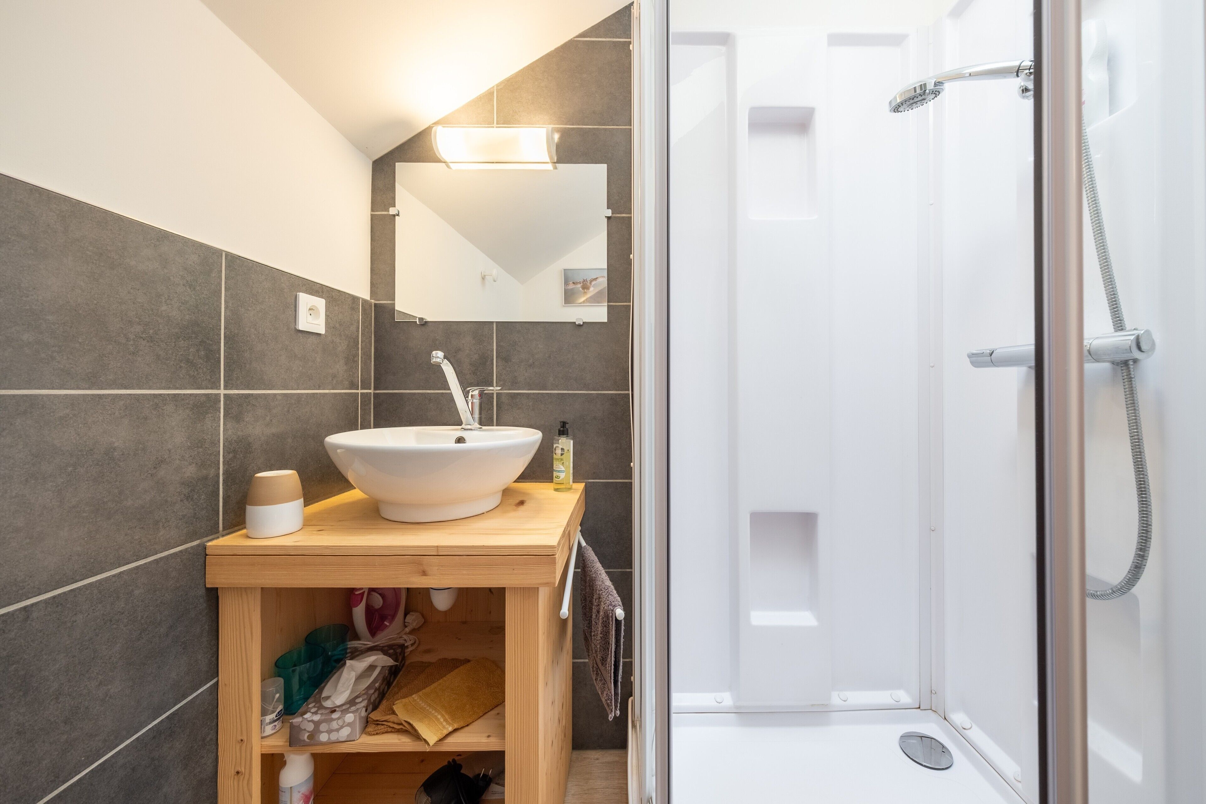 A bathroom with a white sink, mirror, and shower.