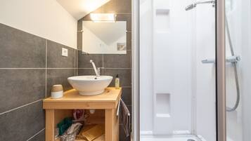 A bathroom with a white sink, mirror, and shower.