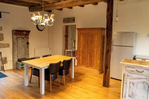 A rustic kitchen with a wooden table and chairs, a refrigerator, and a wooden cabinet. - House 3 on the Embourg estate (Souvigny)
