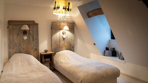 Ein Schlafzimmer mit zwei Betten, einer Chandelieber, einem Holzschrank und einem Fenster mit Blick.