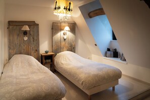 A bedroom with two beds, a chandelier, a wooden wardrobe, and a window with a view. - House 3 on the Embourg estate (Souvigny)
