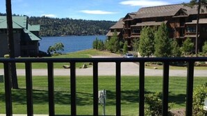 A view of a lodge with a large body of water in the background, a grassy area in the foreground, and a building with a sloped roof.