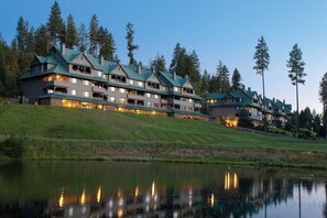 A multi-story hotel with a green roof, located near a body of water and surrounded by trees. - Harrison Idaho | Friends Lake Retreat | Pool + Lake | 2BR (Harrison)