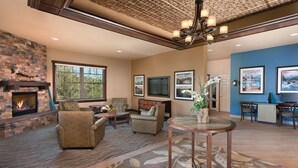 A spacious living room with a fireplace, comfortable seating, a television, and artwork on the walls.