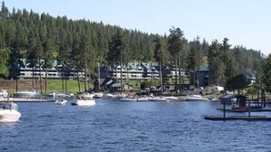 A marina with boats, a lodge, and a forested hill in the background.