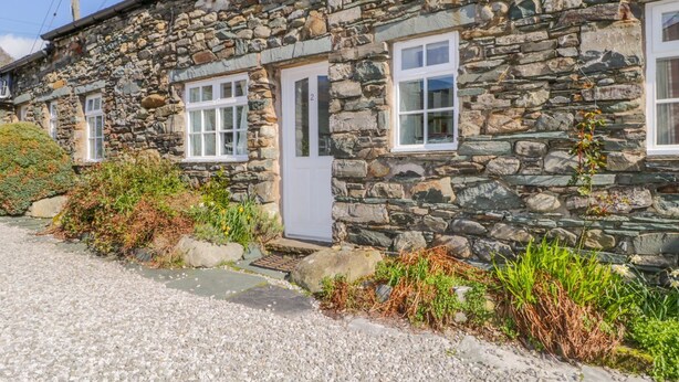 Une maison en pierre avec une allée en gravier et un petit jardin.