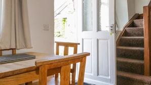Une pièce avec une table et une chaise en bois, une porte blanche portant un numéro et un escalier.