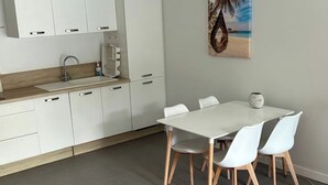 Een moderne keuken met witte kastjes, een houten aanrecht en een eethoek met een witte tafel en stoelen.