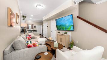 A modern living room with a sofa, coffee table, and a flat-screen TV mounted on the wall.