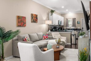 A modern living room with a grey sofa, a coffee table, and a dining area with a kitchen in the background.
