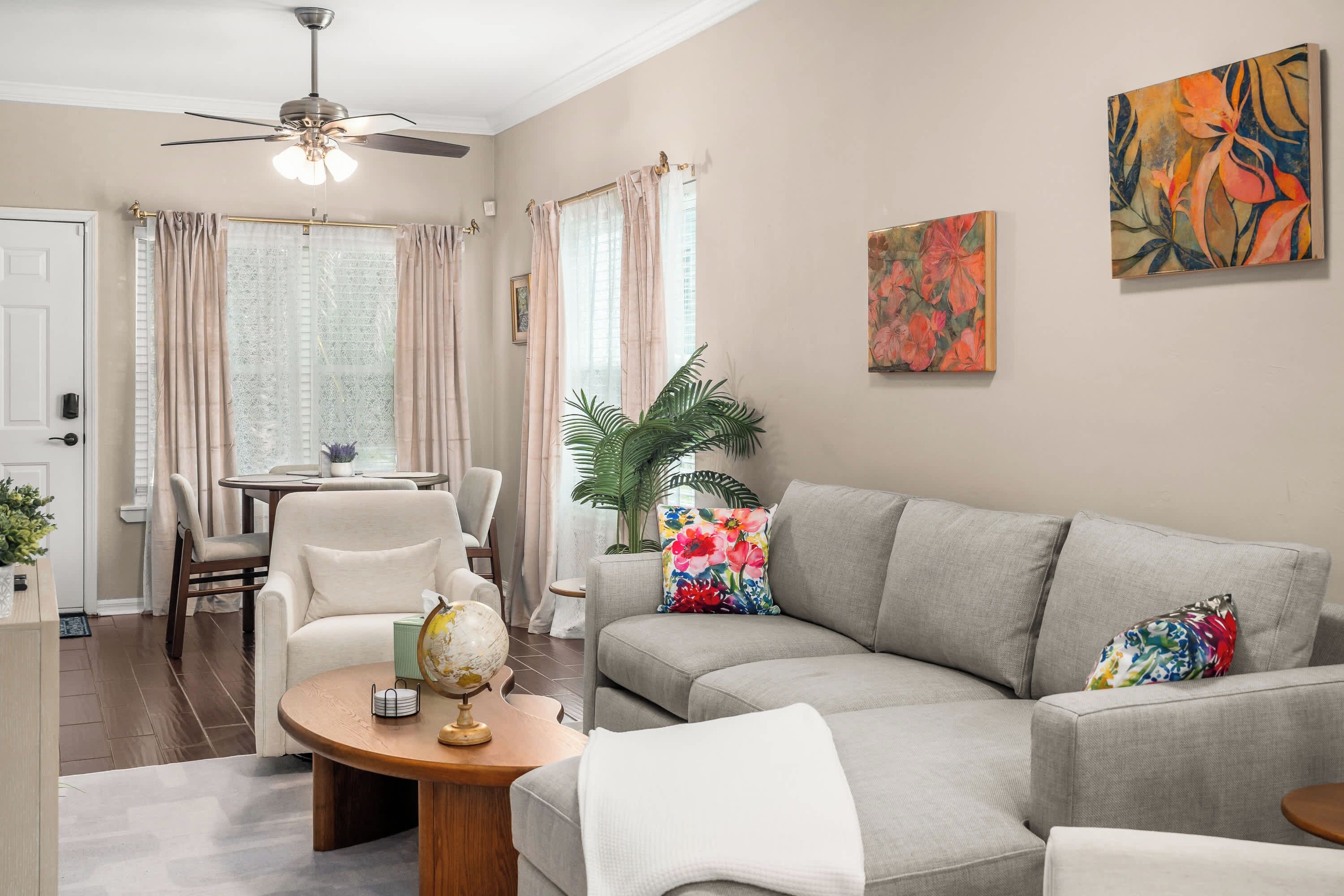 Un salon comprenant un canapé, des fauteuils, une table basse avec un globe terrestre, et un coin repas avec une table et des chaises.