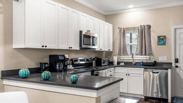 A modern kitchen with white cabinets, stainless steel appliances, and a central island.